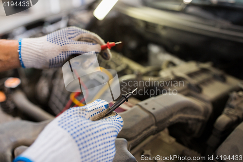 Image of auto mechanic man with multimeter testing battery