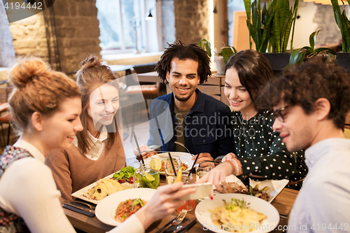 Image of friends with smartphone eating at restaurant