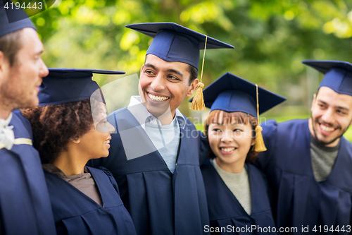 Image of happy students or bachelors in mortar boards