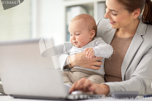 Image of happy businesswoman with baby and laptop at office