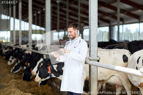 Image of veterinarian with tablet pc and cows on dairy farm