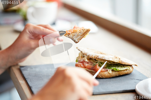 Image of woman eating salmon panini sandwich at restaurant