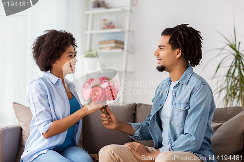 Image of happy couple with bunch of flowers at home