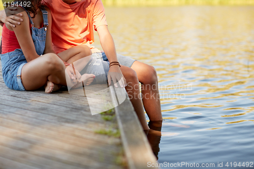 Image of happy teenage couple sitting on river berth