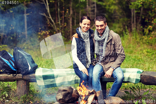 Image of happy couple sitting on bench near camp fire