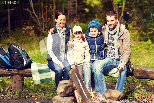 Image of happy family sitting on bench at camp fire
