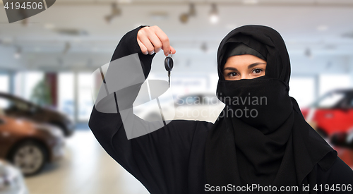 Image of muslim woman in hijab with car key over car show