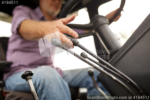 Image of senior man driving tractor at farm