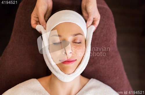Image of woman having face massage with towel at spa