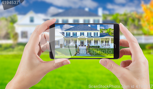 Image of Female Hands Holding Smart Phone Displaying Photo of House Behin