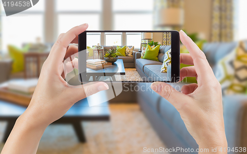 Image of Female Hands Holding Smart Phone Displaying Photo of House Inter