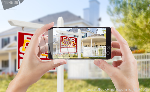 Image of Female Hands Holding Smart Phone Displaying Photo of Sold For Sa