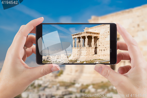 Image of Female Hands Holding Smart Phone Displaying Photo of Caryatids i