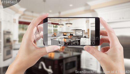 Image of Female Hands Holding Smart Phone Displaying Photo of Kitchen Beh