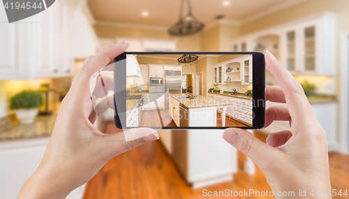 Image of Female Hands Holding Smart Phone Displaying Photo of Kitchen Beh