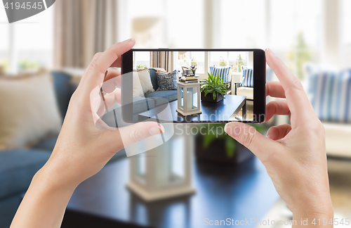 Image of Female Hands Holding Smart Phone Displaying Photo of House Inter