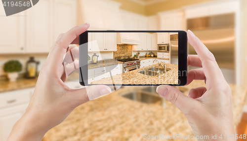 Image of Female Hands Holding Smart Phone Displaying Photo of Kitchen Beh