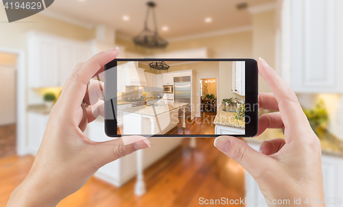 Image of Female Hands Holding Smart Phone Displaying Photo of Kitchen Beh