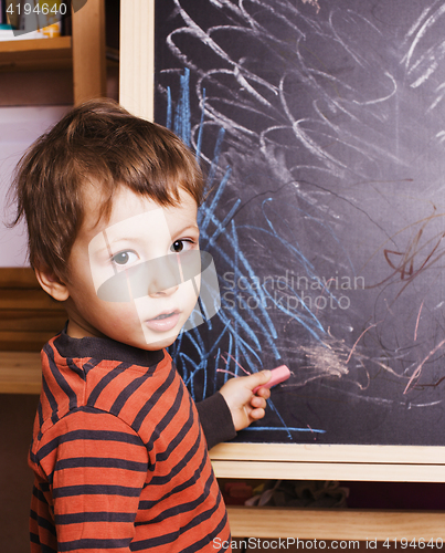 Image of little cute boy with young teacher in classroom studying at blackboard smiling, doing homework