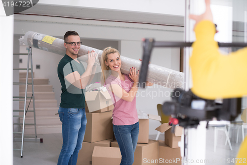 Image of couple carrying a carpet moving in to new home