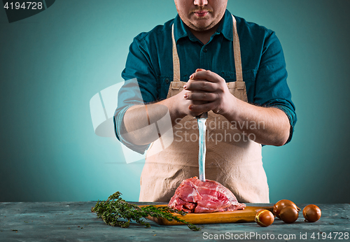 Image of Butcher cutting pork meat on kitchen