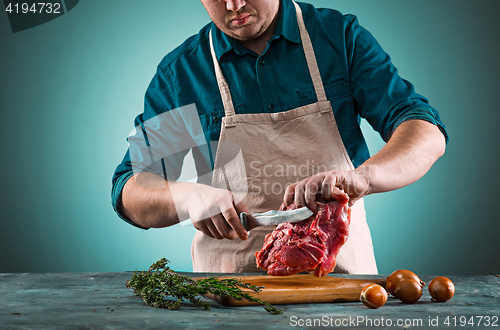 Image of Butcher cutting pork meat on kitchen