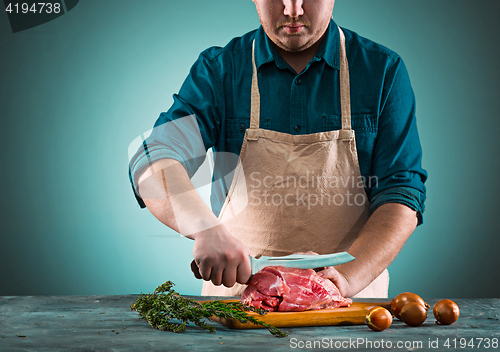 Image of Butcher cutting pork meat on kitchen