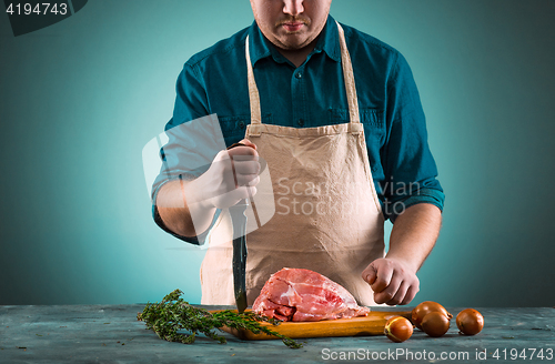 Image of Butcher cutting pork meat on kitchen