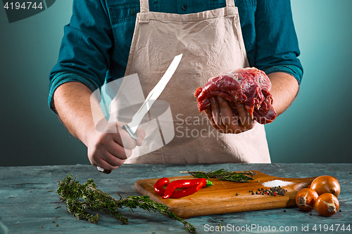 Image of Butcher cutting pork meat on kitchen