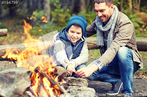 Image of father and son roasting marshmallow over campfire