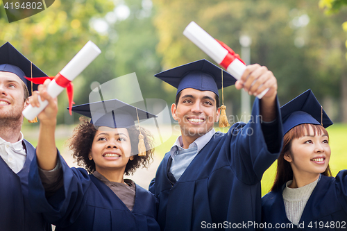 Image of happy students in mortar boards with diplomas