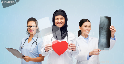 Image of happy doctors with red heart, x-ray and clipboard