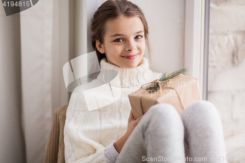 Image of girl with christmas gift sitting at home