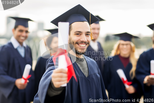 Image of happy students in mortar boards with diplomas