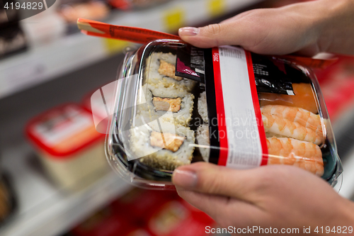 Image of hands with sushi pack at grocery or supermarket