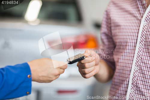 Image of auto mechanic giving car key to man at workshop