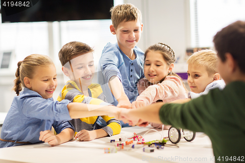 Image of happy children making fist bump at robotics school