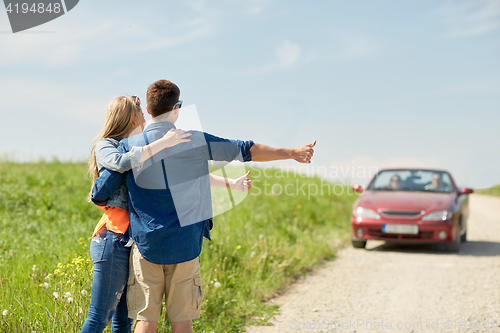 Image of couple hitchhiking and stopping car on countryside