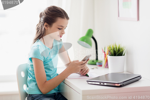Image of girl with laptop and smartphone texting at home