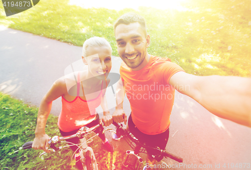 Image of couple with bicycle taking selfie outdoors