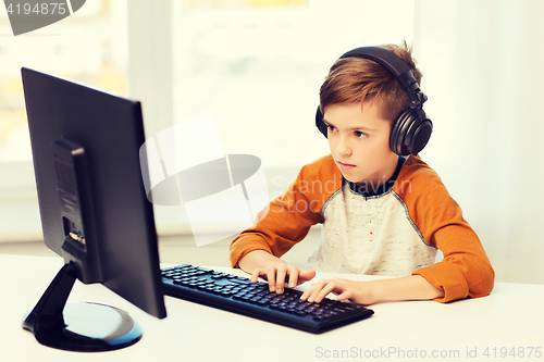Image of boy with computer and headphones at home