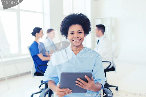 Image of happy nurse with tablet pc over team at hospital