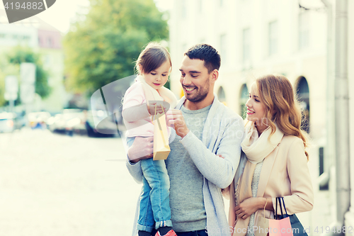 Image of happy family with child and shopping bags in city