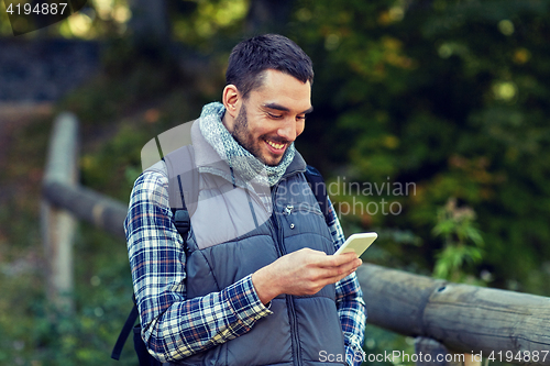 Image of happy man with backpack and smartphone outdoors