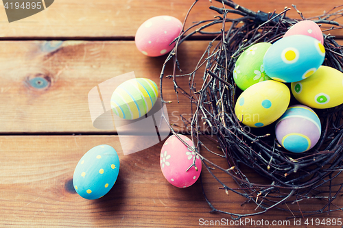 Image of close up of colored easter eggs in nest on wood