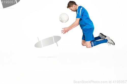 Image of Young boy with soccer ball doing flying kick