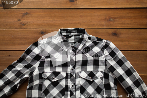 Image of close up of checkered shirt on wooden background