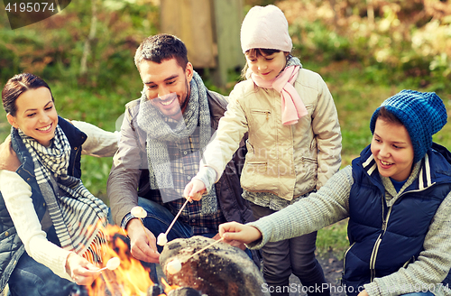 Image of happy family roasting marshmallow over campfire