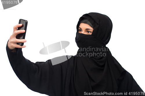 Image of muslim woman in hijab taking selfie by smartphone