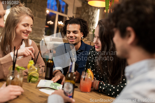 Image of friends with drinks, money and bill at bar
